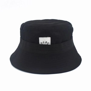 Detailed view of black bucket hat featuring a white square patch with a black smiley face