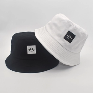 Close-up of black and white cotton bucket hats with smile logo patches and stitched brims