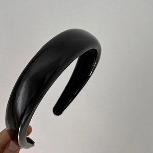 Close-up of a wide black glossy headband with a sleek polished finish for women