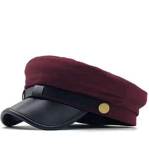 Detail of burgundy newsboy cap with black leather visor and gold metal side buttons