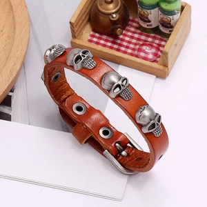 Detail of brown leather punk bracelet with silver metal skull studs and buckle strap