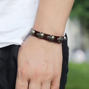 Men's retro brown leather bracelet with bronze skull charms in outdoor setting