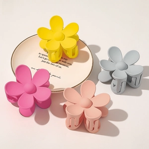 Detail of matte flower hair claws in muted yellow, blue, pink and apricot tones
