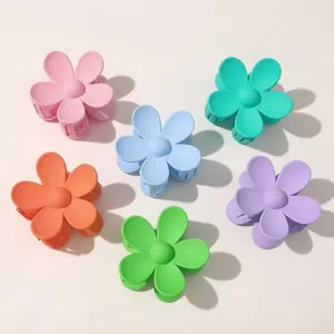 Détail de six pinces à cheveux fleurs mates colorées en rose, bleu, vert et violet