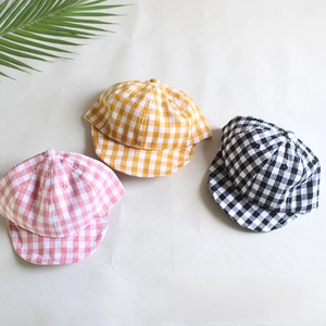 Flat lay of baby cotton plaid caps in pink, yellow, and black colors with soft brims