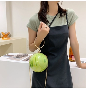 Detail of green acrylic ball evening bag with marble texture and gold metal handle