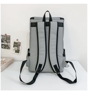 Rear view of a grey large capacity travel backpack with black straps on a clean table