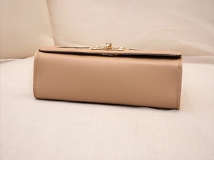 Detailed view of textured PU leather and golden twist lock on light brown crossbody bag