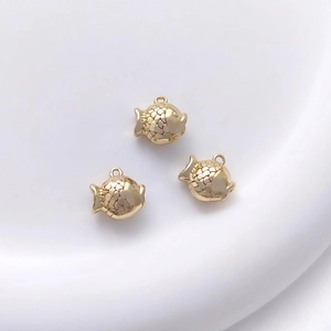Macro detail of 14K gold plated fish pendants with intricate scale textures for DIY jewelry