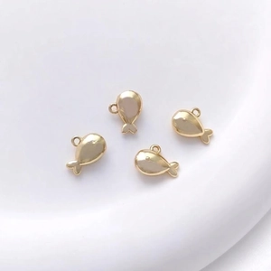 Close-up of four 14K gold-plated whale pendants for DIY jewelry making with mirror finish