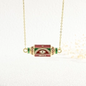 Detail of gold evil eye necklace pendant with red green enamel and inscribed WILL text
