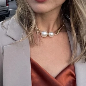 Detail of chunky gold chain necklace with large twin pearls on a model neck
