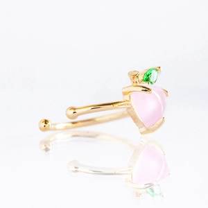 Macro shot of gold-plated pink peach ear cuff with sparkling zircon fruit detail