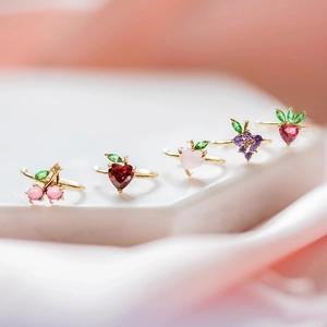 Macro shot of five gold fruit rings with colorful zircon cherry and peach crystal details