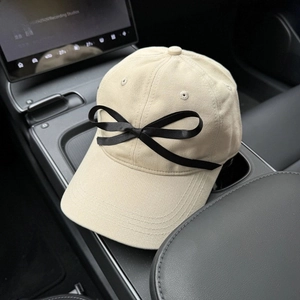 Detail of beige cotton baseball cap with a black satin bow on the front seat of a car