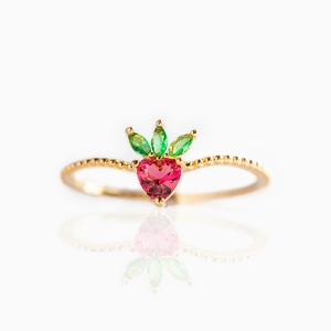 Macro shot of gold strawberry ring with pink heart stone and green leaf detail