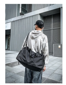 Detail of a matte black waterproof travel bag with reinforced straps and side pocket