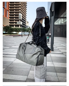 Grey waterproof nylon travel bag shown in an urban setting with adjustable shoulder strap
