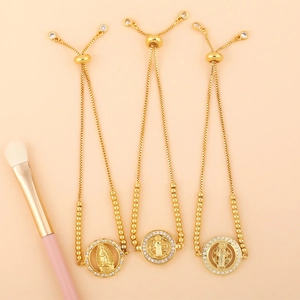 Three adjustable gold zircon bracelets with religious medallions on a soft pink background