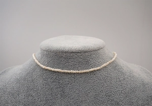 Detail of a mini freshwater pearl necklace on a grey jewelry bust display stand