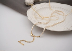 Detailed close-up of mini freshwater pearl necklace draped on an elegant ceramic plate