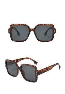 Detail view of tortoiseshell oversized square sunglasses with textured temples and gray lenses