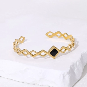 Minimalist gold geometric bangle with black diamond-shaped inlay on stone