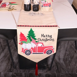 Linen Christmas table runner with Santa car print and red tassels on marble table