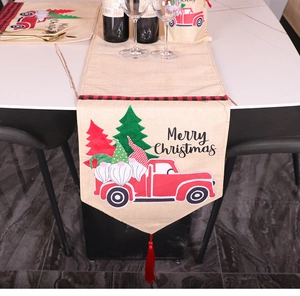 Detailed close-up of Christmas table runner with red truck, gnome patterns and tassels
