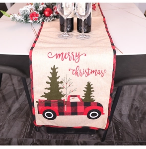 Close-up of burlap Christmas table runner with red truck pattern and Merry Christmas text