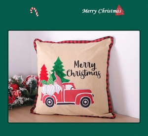 Macro detail of Christmas gnome cushion cover with red truck and festive buffalo plaid border
