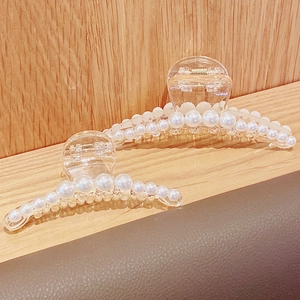Elegant pearl hair claws in two sizes displayed on a wooden surface with a warm aesthetic