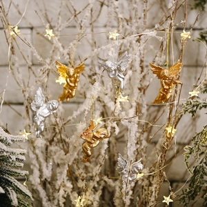 Creative gold and silver Christmas angel ornaments hanging on snowy festive tree branches