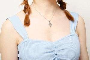 Close-up of a silver dolphin pendant necklace worn by a model in casual summer style