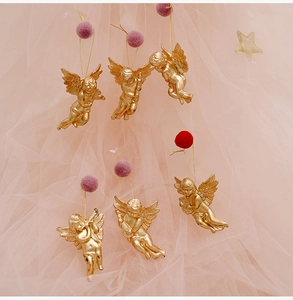 Set of 6 golden Christmas angel ornaments in diverse poses on a dreamy pink background
