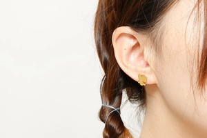 Gros plan de boucles d'oreilles papillon dorées portées par un mannequin en détail