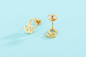 Détail de boucles d'oreilles puces en forme de cœur évidé avec ailes dorées
