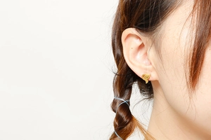 Close-up of a gold hollow fox-shaped stud earring worn on a model's ear