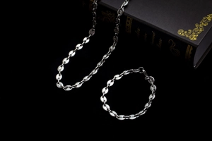 Macro detail of polished stainless steel coffee bean link necklace and bracelet set