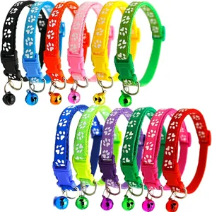 Colorful pet collars with white paw prints, bells and plastic buckles on a white background