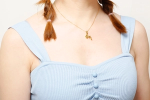 Close-up of a hollowed animal flamingo pendant necklace in gold finish worn by a model