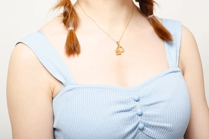 Détail d'un collier doré avec pendentif nœud papillon porté par un mannequin élégant