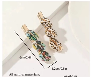 Detailed view of hair clips with shell patterns and gold metal base displayed on a stand