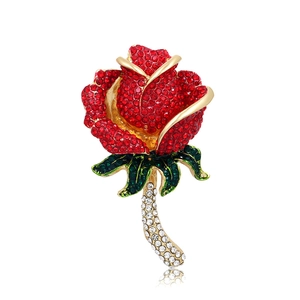 Close-up of red rhinestone rose brooch with green enamel leaves on a gold base