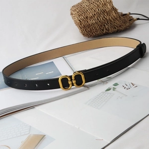 Detail of a thin black leather belt with a vintage gold double round buckle over props