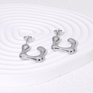 Irregular lava style silver stainless steel stud earrings on a rippled display stand
