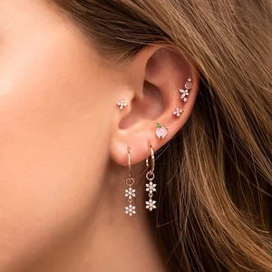 Close-up of rose gold zircon earring set featuring flower charms and peach studs