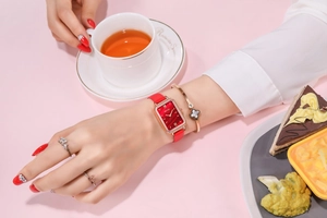 Detail of elegant rectangular rose gold watch with red leather strap on woman wrist
