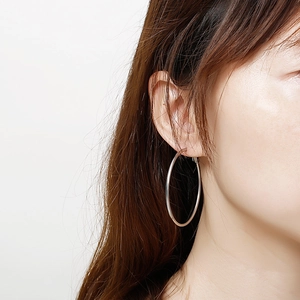Créoles minimalistes en acier inoxydable poli pour femme portées par un mannequin