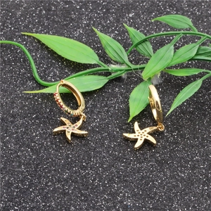 Golden starfish earrings with multicolored cubic zirconia on a black glitter background